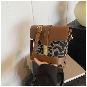 Detailed close-up of leopard print bucket bag featuring a golden twist lock and leather strap