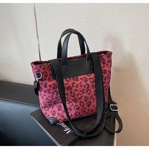 Detailed shot of red leopard print tote bag with black leather handles and wide strap