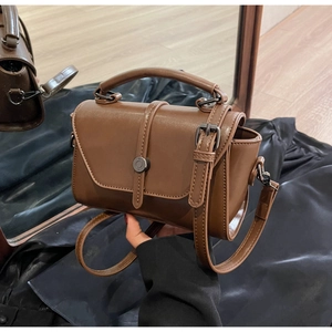 Close-up of vintage brown crossbody bag with metal buckle and textured flap detail