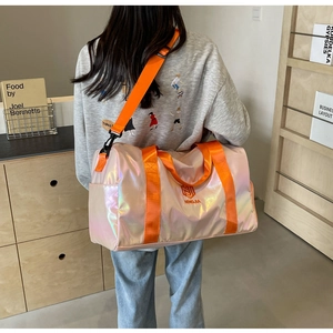 Detail of pink pearlescent gym bag with orange straps shown on person's back