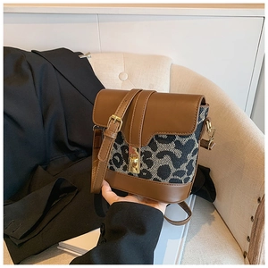 Detail view of the brown leather stitching with leopard print canvas and gold buckle