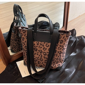 Detail of leopard print canvas bucket bag with black leather trim and wide shoulder strap