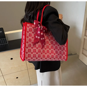 Detail of red Xi character embroidery on beige woven tote bag with silk scarf