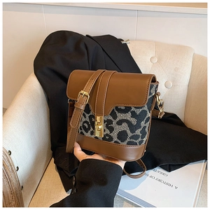 Detail of leopard print bucket bag featuring brown leather trim and golden twist lock