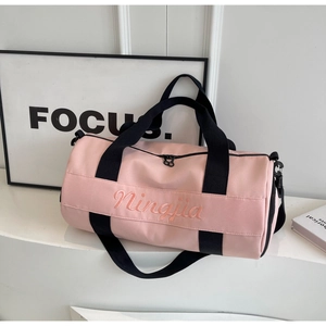 Detail of pink cylindrical sports bag featuring Ningjia embroidery on a premium white stand
