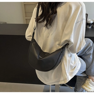 Détail du sac bandoulière noir en forme de croissant avec logo OOMT porté par mannequin
