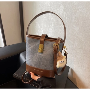 Detail van vintage denim bucket bag met lederen bies en pluche pop hanger