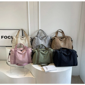 Groupe de grands sacs de voyage en six coloris exposés sur des socles blancs épurés