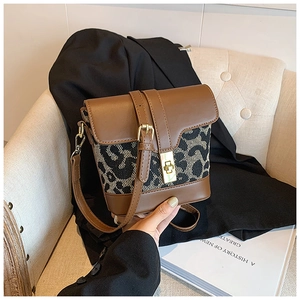 Close-up of leopard print crossbody bag with brown leather details and gold metal lock