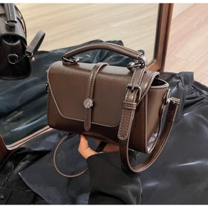 Detailed shot of dark brown glossy leather handbag with metallic ring and handle