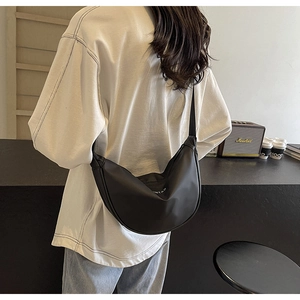 Sac bandoulière demi-lune en nylon noir tendance porté par une personne en intérieur