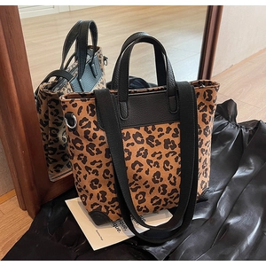 Detail view of leopard print tote bag with black leather trim and wide canvas shoulder strap