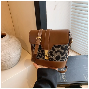 Detail of leopard print bucket bag with brown leather flap and golden twist lock clasp