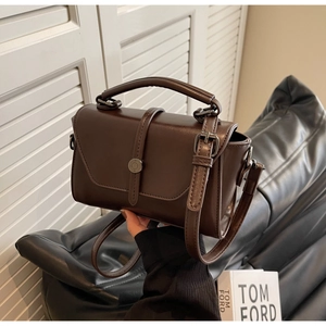 Detail view of the deep brown faux leather texture and metallic buckle on the handbag