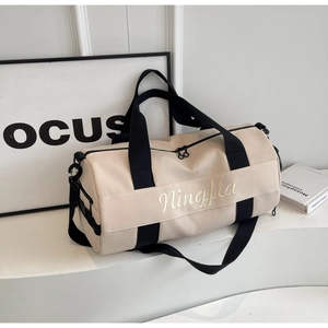Detail of beige gym bag featuring brand embroidery and black adjustable shoulder strap