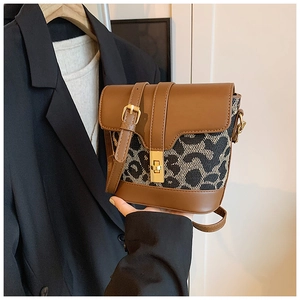 Detail of leopard print bucket bag featuring brown leather trim and golden twist lock