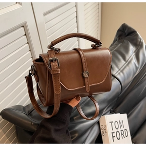 Close-up of vintage brown PU leather handbag with metal twist lock and matte finish