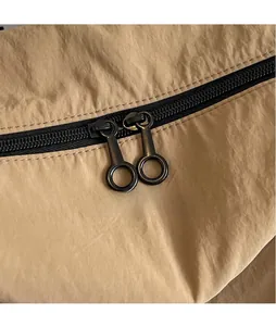 Détail de la tirette ronde en métal lisse sur un sac de voyage en nylon durable