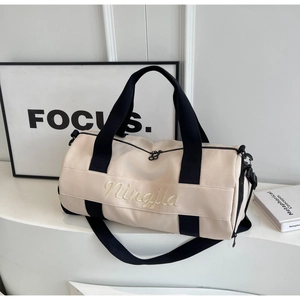 Detailed view of the cylindrical fitness bag featuring cream canvas and gold Ningjia embroidery