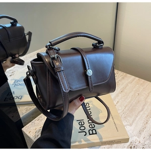 Detail of dark brown vintage handbag with polished finish and circular metallic buckle