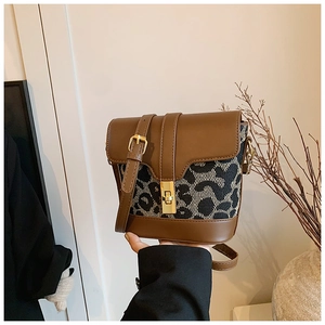 Detail of leopard print bucket bag featuring brown leather trim and golden square lock