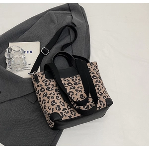 Detailed view of leopard print tote bag with black strap and reinforced base on a stylish desk