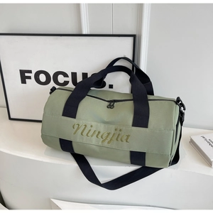 Side view of light green fitness duffel bag with gold branding and black straps