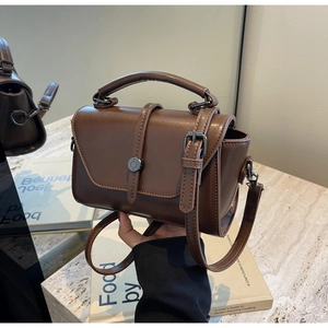 Close-up of vintage brown leather handbag with round metallic buckle and handle