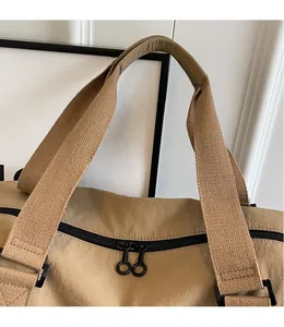 Détail du sac de voyage kaki montrant la bandoulière tissée et les fermetures éclair doubles