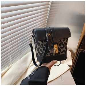 Close-up of leopard print crossbody bag with gold rotating clasp and matte leather trim