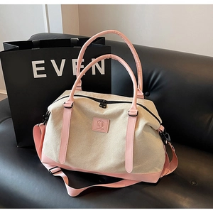 Close-up of beige canvas travel bag with pink leather handles and detachable shoulder strap