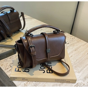 Detail view of deep brown vintage matte leather bag with flap and metal buckle