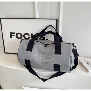 Gray cylindrical fitness duffel bag with black straps and adjustable shoulder strap