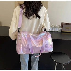 Iridescent purple travel bag with wide shoulder strap shown on model in modern setting