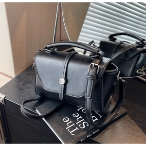 Detail of vintage black leather handbag with silver buckle and adjustable shoulder strap