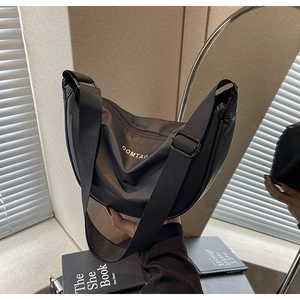 Détail du sac hobo en nylon noir avec logo OOMTAO et bandoulière large ajustable