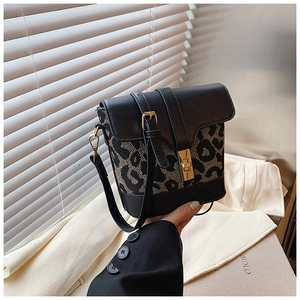 Detail showing leopard print fabric texture and gold turn-lock closure on bucket bag