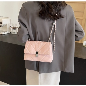 Close-up of pink quilted fabric shoulder bag with silver metal lock and chain strap