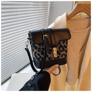 Detail of leopard print bucket bag featuring gold twist lock and black faux leather strap