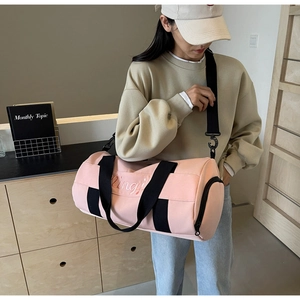Detailed view of pink cylinder sports bag featuring embroidery and adjustable shoulder strap