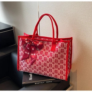 Detail of red bridal tote bag featuring festive Xi patterns and decorative bow accent