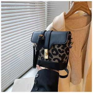 Detail of leopard print bucket bag with black leather flap and gold metal twist lock