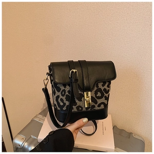Close-up of leopard print bucket bag with contrast leather and gold twist lock closure