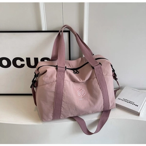 Détail du sac de voyage rose avec logo brodé et bandoulière réglable amovible