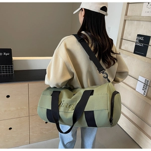 Olive green travel duffel bag with gold embroidery shown in a stylish lifestyle setting