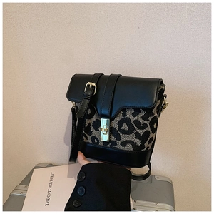Detail of leopard print bucket bag with gold twist lock on silver luggage background