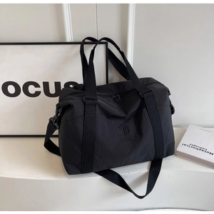 Vue détaillée du sac de voyage en nylon noir avec logo, poignées et bandoulière réglable