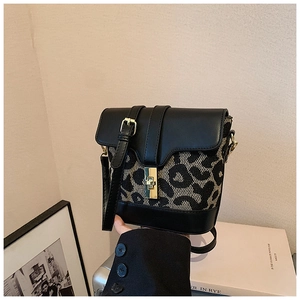 Detail of leopard print canvas and black leather crossbody bag with gold buckle