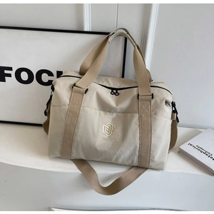 Détail du sac de voyage beige avec bandoulière large et poignée de transport tissée