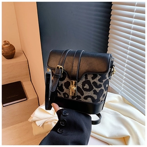 Detailed close-up of leopard print bucket bag with gold hardware and black leather flap